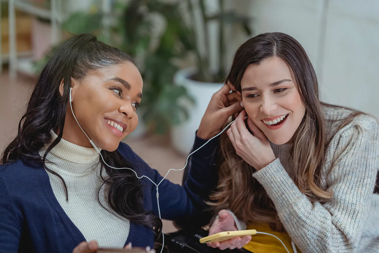 deux amies écoutant de la musique en se partageant les écouteurs