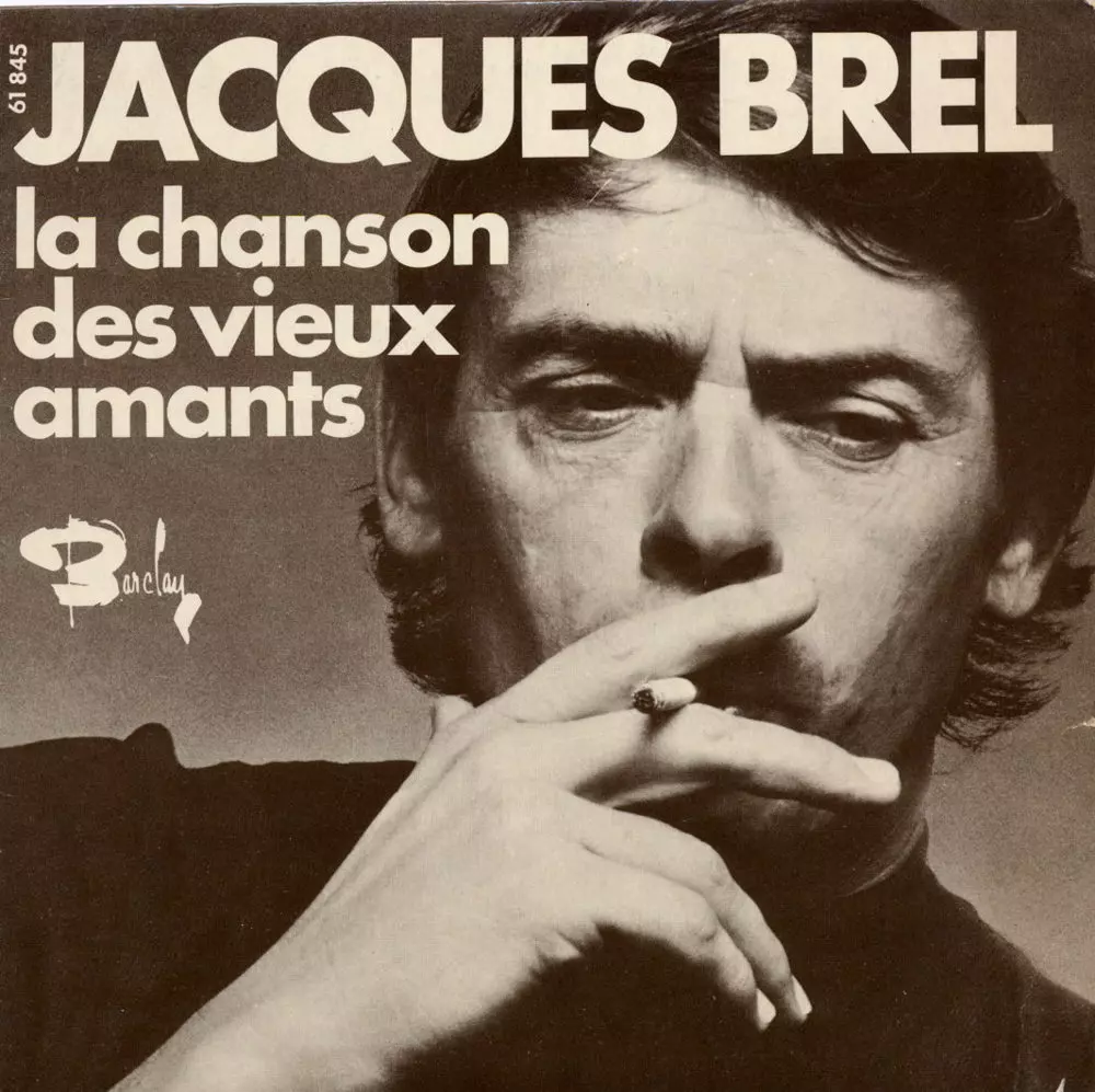 Gros plan en sépia sur Jacques Brel, regardant vers le bas fumant une cigarette