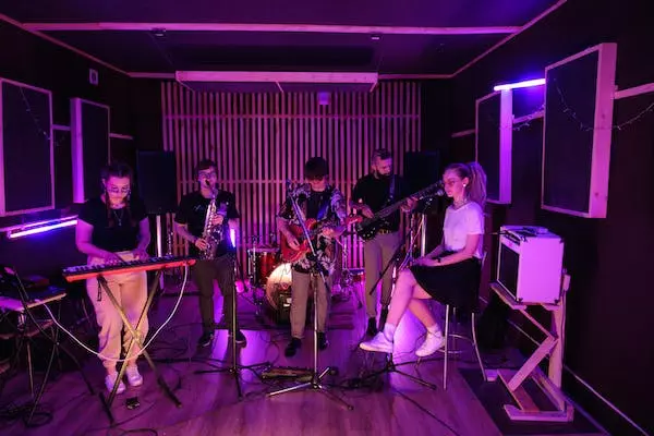 5 personnes en train de chanter et jouer de la musique dans un studio d'enregistrement