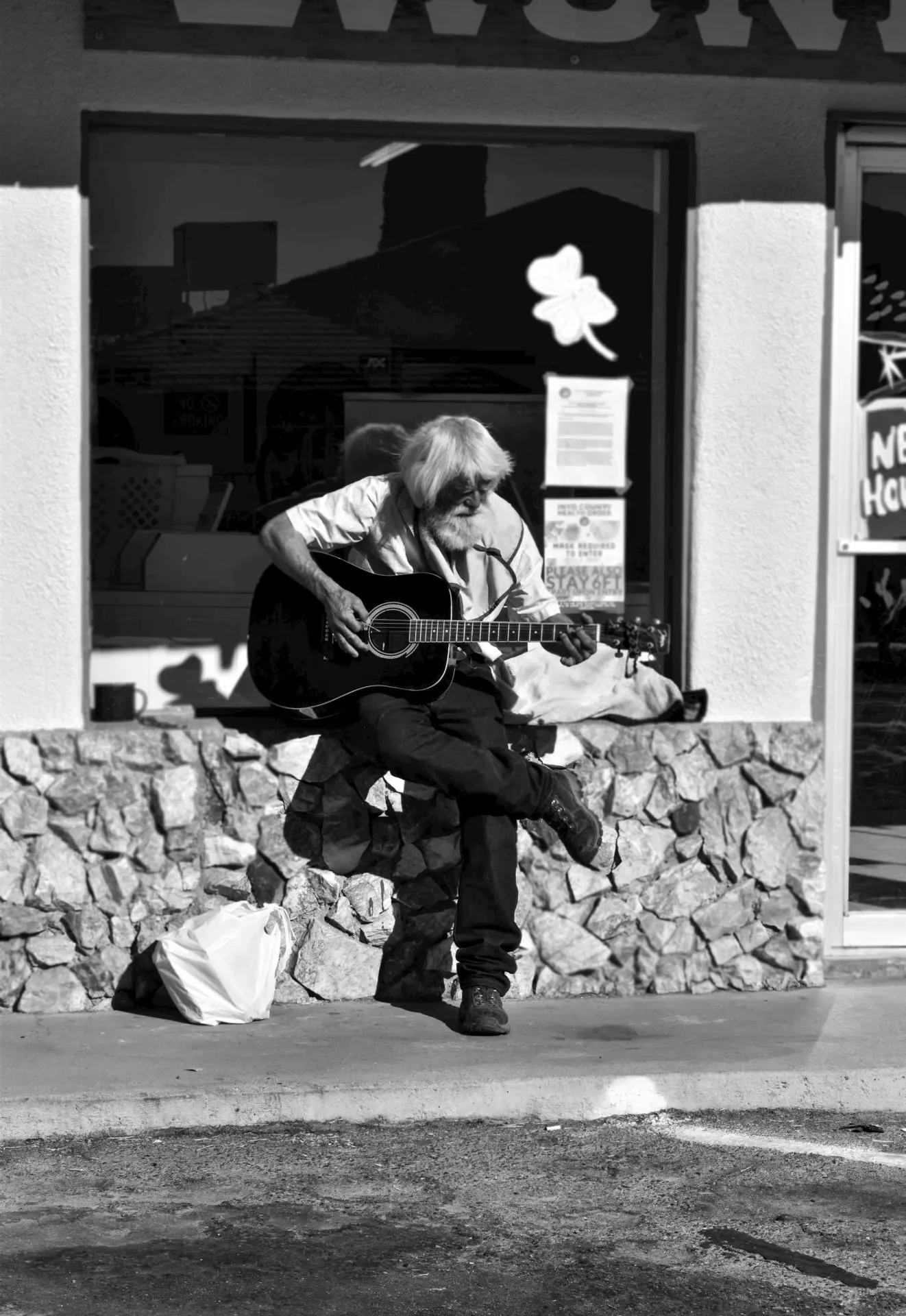 Une personne âgé joue de la guitare dans la rue 
