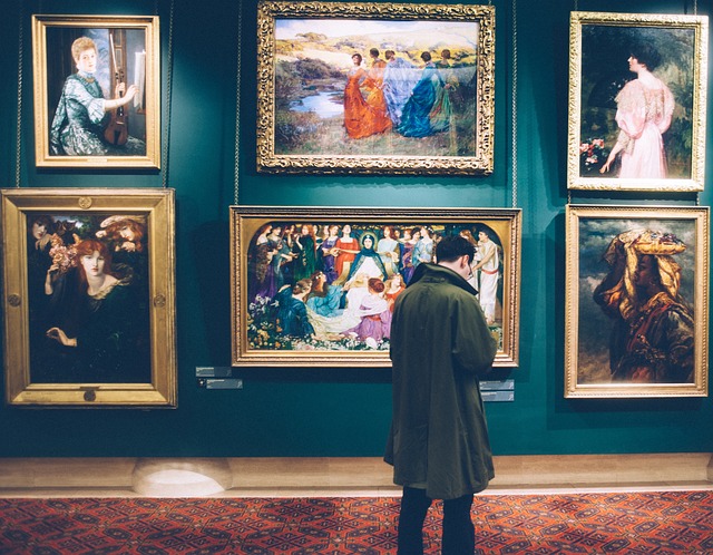 Homme devant des tableaux d'art au sein d'un musée
